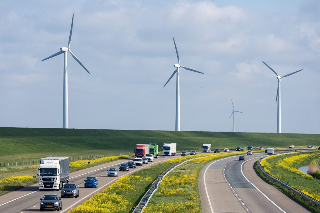 Lean & Green International - Photo showing trucks driving on a street next to wind turbines